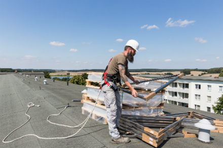 Heizungsbaumeister Lars Ost prüft auf dem Dach die gerade angelieferten Bauteile für die Solaranlage.