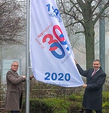 HZD-Direktor Joachim Kaiser (l.) und Technischer Direktor Thomas Kaspar hissen die Jubiläumsflagge vor der HZD-Zentrale. 