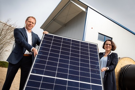Der REWAG-Vorstandsvorsitzende Torsten Briegel und Oberbürgermeisterin Gertrud Maltz-Schwarzfischer mit einem Solar-Modul vor der neuen PV-Anlage.