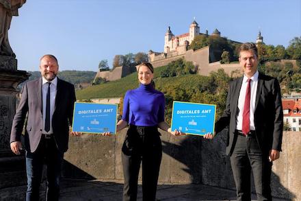 Digitalministerin Judith Gerlach übergibt Würzburgs Landrat Thomas Eberth (links) und Oberbürgermeister Christian Schuchardt ihre Auszeichnungen zum Digitalen Amt.