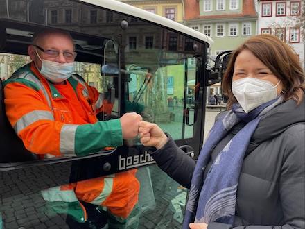 Aus seiner neuen E-Kehrmaschine heraus begrüßt Udo Junge die Thüringer Umweltministerin Anja Siegesmund mit der Faust.