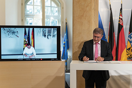 Der saarländische Innenminister Reinhold Jost (online) und der sächsische CIO Thomas Popp unterzeichnen die Kooperationsvereinbarung Online-Wache.