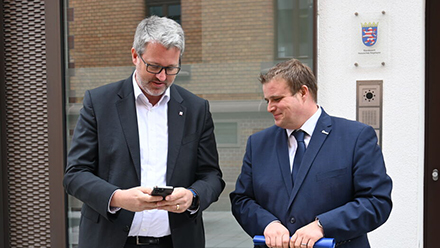Digitalstaatssekretär Patrick Burghardt (l.) und Bürgermeister Benjamin Tschesnok bei der Inbetriebnahme der 2.000sten Digitalen Dorflinde in der Hünfelder Rathausstraße.