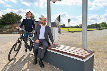 Ausruhen und Equipment laden: CDO Denes Kücük (l.) und Stadtdirektor Sebastian Kopietz probieren Bochums erste smarte Sitzbank aus.
